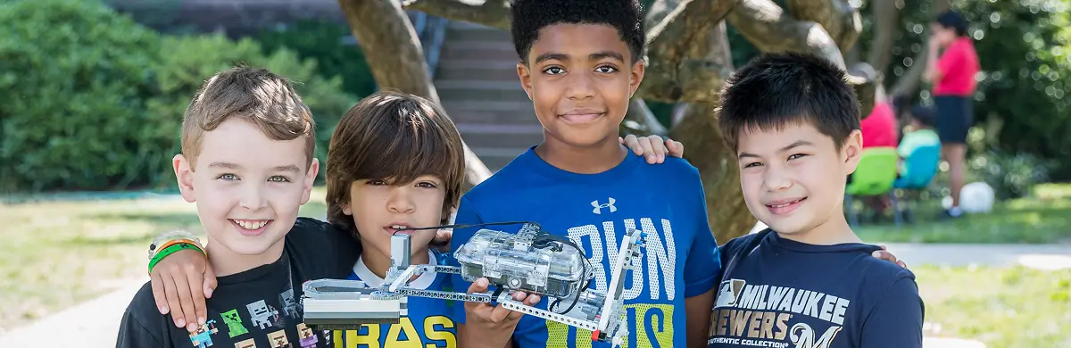 Four children at summer camp showing off their stem construction
