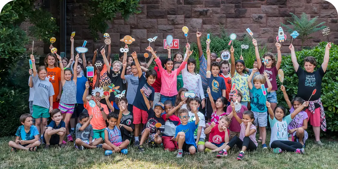A group of children at summer camp cheering arms in the air